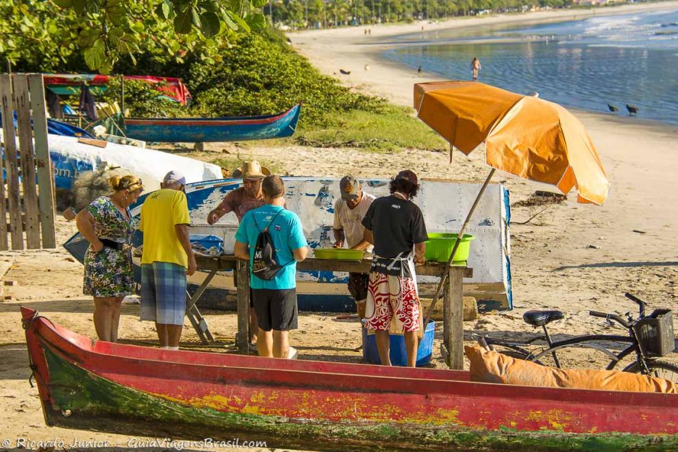 Imagem de turistas comprando pescados na Praia do Itaguá.